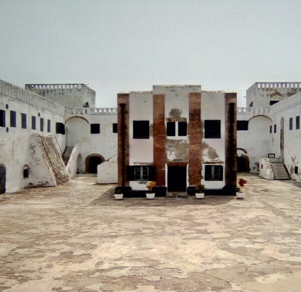 The inner courtyard of a historic coastal fort in Ghana, with whitewashed colonial buildings