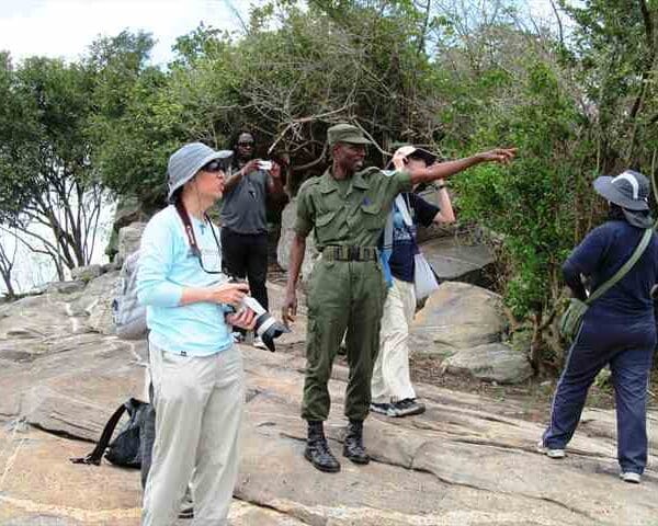 A tour group with a park ranger on a rocky outcrop in Ghana, looking out over the bush