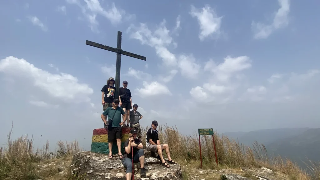 A guided tour group gathered at the summit cross above Amedzofe in Ghana Volta Region.