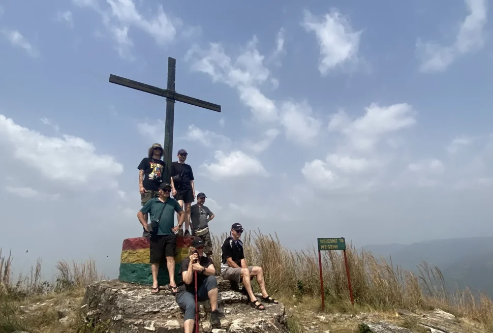 A guided tour group gathered at the summit cross above Amedzofe in Ghana Volta Region.