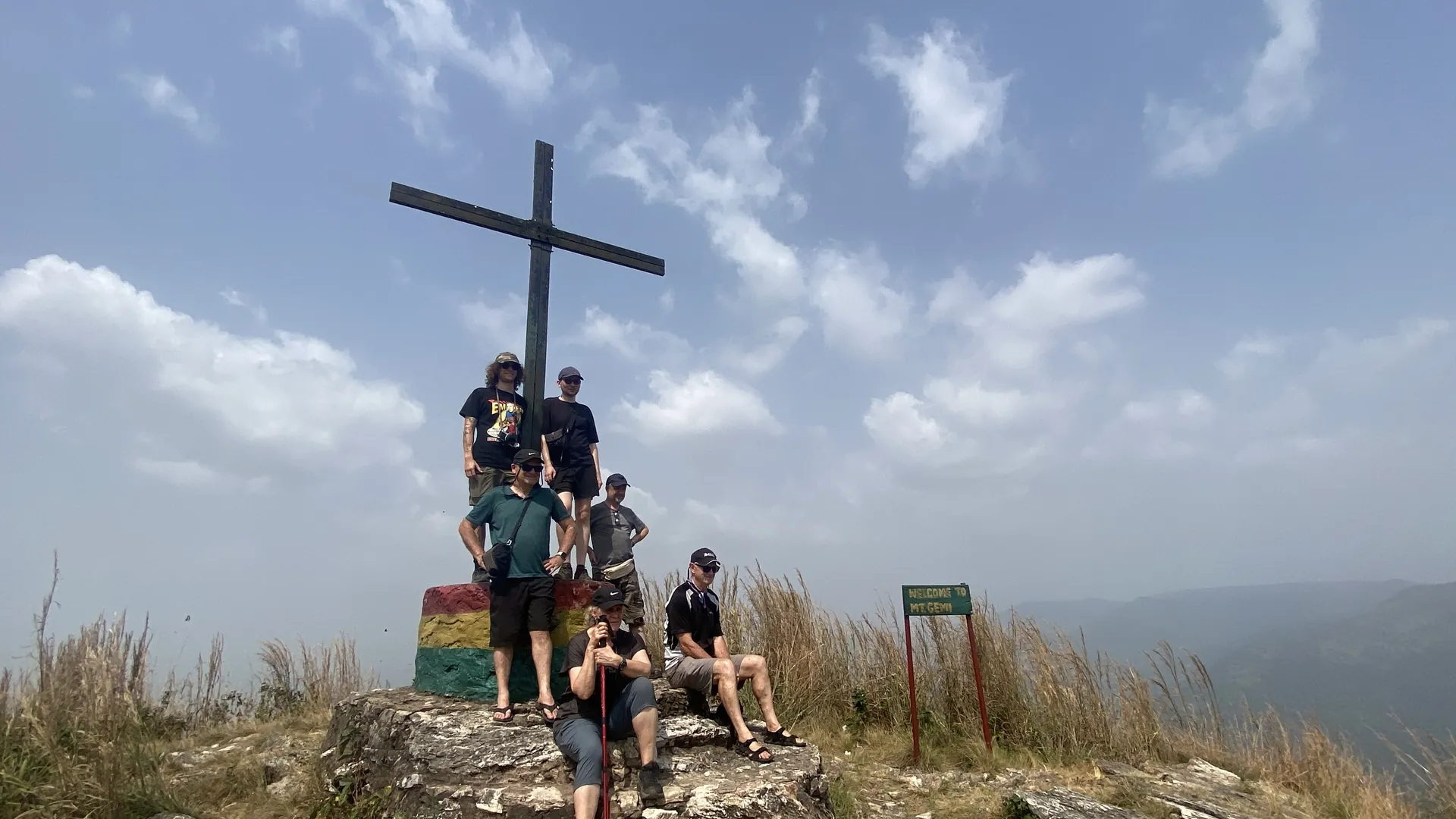 A guided tour group gathered at the summit cross above Amedzofe in Ghana Volta Region.